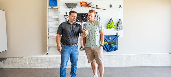 Two men looking at a phone with wall storage behind them